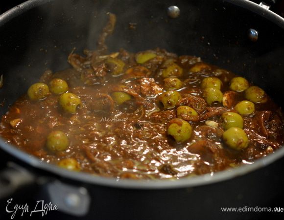 Разогреть оливковое масло на сковороде, обжарить мелко порубленный лук, мелко порезанный зеленый лук, чеснок. Помешиваем и готовим 2-3 мин. Добавить все сухие специи. Готовить 1 мин. Добавить томатную пасту, оливки, изюм, воду.