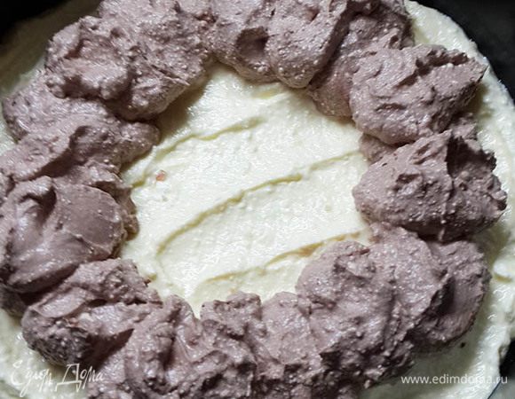 Получившийся творожный крем разделить на 2 части: на 1/3 и на 2/3. В меньшую часть высыпать какао, хорошо размешать. Выложить половину белого крема на корж. Затем ложкой выложить коричневый крем по форме кольца.