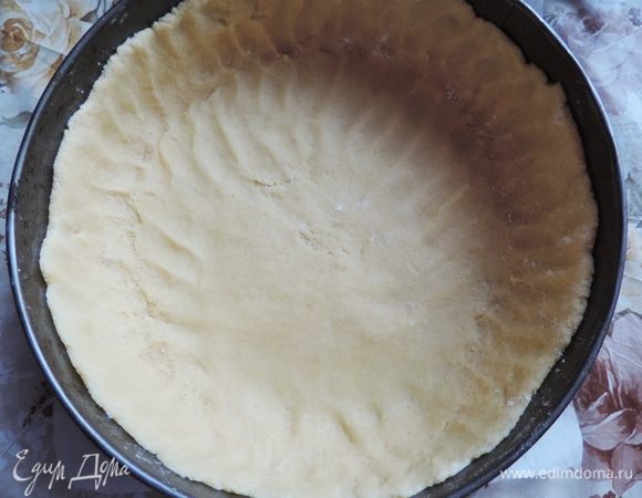 Форму диаметром 26 см застелить бумагой, распределить тесто по форме, формируя высокие бортики. Для удобства, руки можно немного припудривать мукой.
