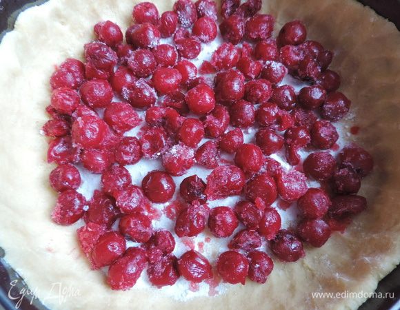 Вишню разморозить, сок слить. Приготовить крахмальную посыпку — она не даст вишне пустить сок и размочить тесто. Благодаря наличию крахмала получится слой вишни в густом киселе. Смешать сахар с крахмалом. Треть смеси высыпать на тесто, выложить слой вишни.