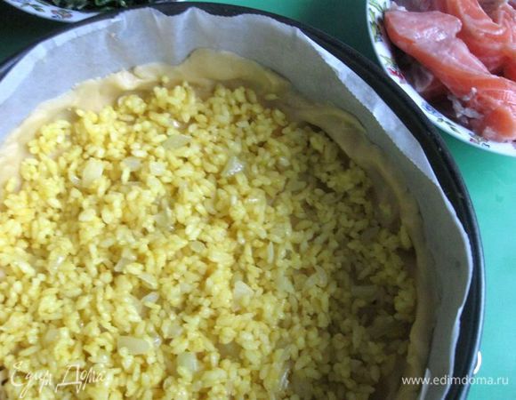 Филе лосося порезать на крупные кусочки, твердый сыр натереть на крупной  терке.
Духовку разогреть до 195°C.
Положить часть риса с луком (140 г) на тесто.

