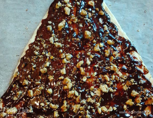 Посыпать орехами. Так поступить со всеми пластами, сложив их друг на друга.