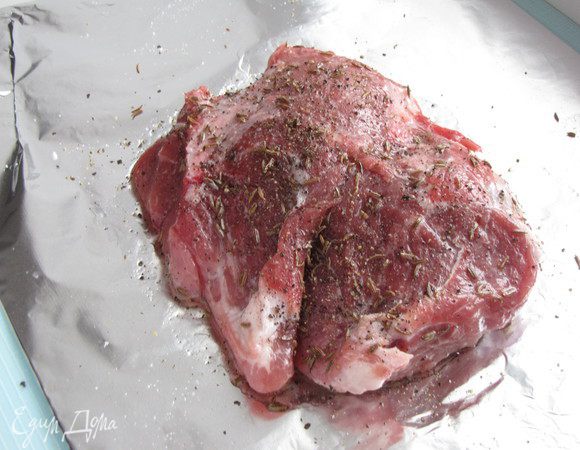 На фольгу, сложенную в два слоя, налить масло, сверху на масло положить кусок свинины. Посыпать обильно солью, тмином, черным перцем. Все хорошо смешать и втереть в кусок свинины.