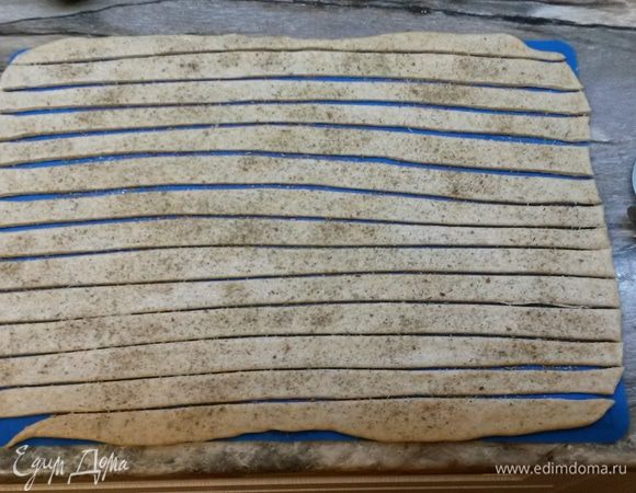 Смазываем тесто водой, посыпаем сухими травами или маком. Ножом для пиццы разрезаем тесто на полоски шириной 1.5 см.