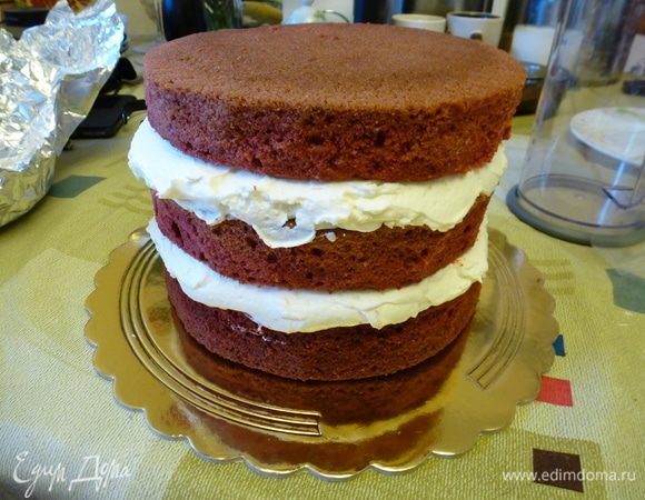 На подложку для торта кладем первый корж. Сверху намазываем примерно 1/3 крема. Далее второй корж и следующую 1/3 часть крема. Выкладываем третий корж.