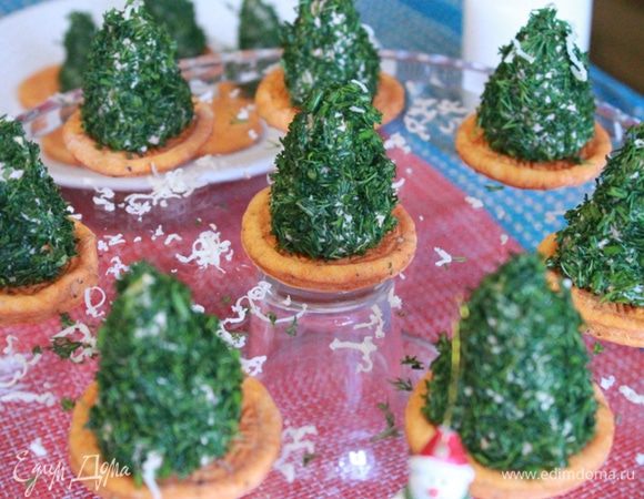 Затем обваливаем со всех сторон (дно елки в укроп не ставим, нам надо, чтобы она хорош зафиксировалась — прилипла к крекеру) в укропе.
На каждый крекер ставим нашу зеленую красавицу. Вот на этом этапе под каждую елочку можно положить кружочек соленой красной рыбки.