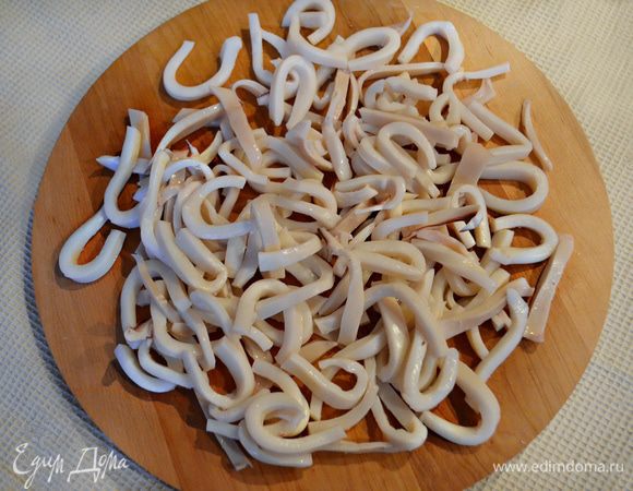 Нарезать отваренные и охлаждённые кальмары соломкой.