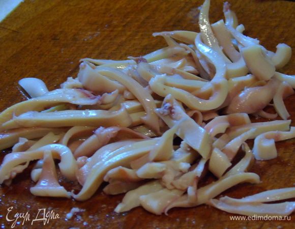 Кальмары очищаем, промываем и отвариваем 20-30 секунд в кипящей воде. Достаем и сразу же под холодную воду, а затем нарезаем полосочками.