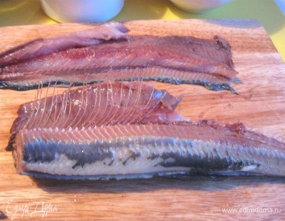 Взять за хвост двумя руками с противоположных сторон. Круговым движением перевернуть на себя сельдь («сальто»), не отпуская хвост; потом потянуть резко хвост в разные стороны. У вас будет две части: кожа с чистым филе и другая часть кожи с хребтом, реберными костями и частью филе. Удалить хребет и реберные кости.