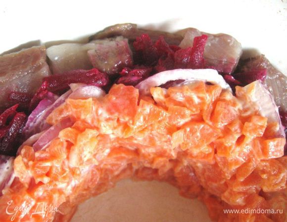 Миску смазать растительным маслом. Уложить по кругу кусочки филе сельди. Затем по кругу — слой свеклы, красного лука, моркови, тертого яблока.