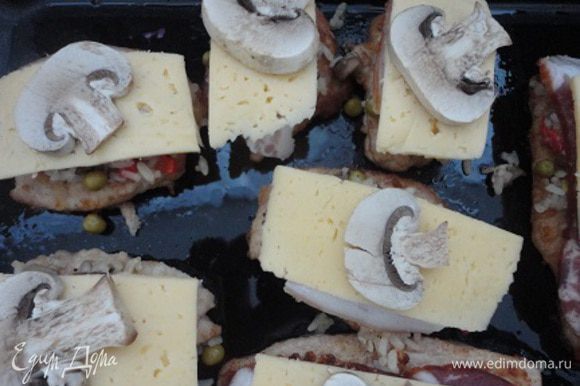 Мясо выложить на противень и покрыть слоем начинки. Сверху положить по кусочку бекона и сыра. Украсить отложенными кусочками грибов.