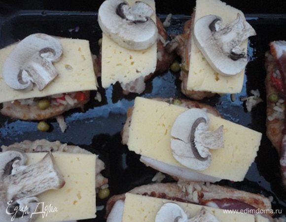 Мясо выложить на противень и покрыть слоем начинки. Сверху положить по кусочку бекона и сыра. Украсить отложенными кусочками грибов.