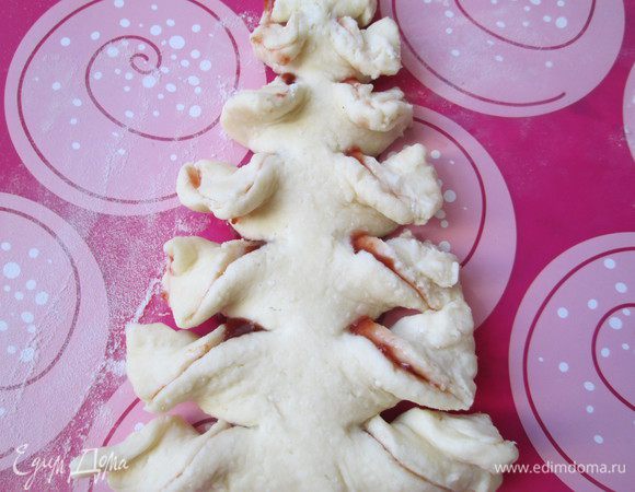 Лучше лепить елочки сразу на противне, застеленном пекарской бумагой или силиконовым ковриком. Каждую полоску закручиваем в спираль — получаются пушистые еловые веточки.