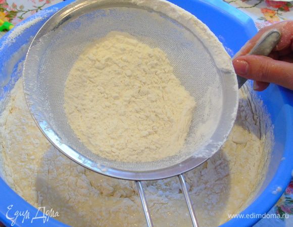 И начинаем постепенно добавлять муку, мука у меня уже просеянная, но все же я ее еще раз просеиваю, а тесто мешая ложкой.