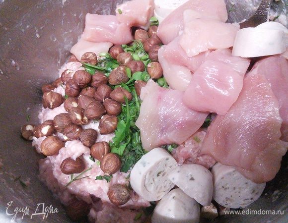 В фарш добавить орешки, зелень, кусочки курицы и колечки колбасок и аккуратно вымешать. 