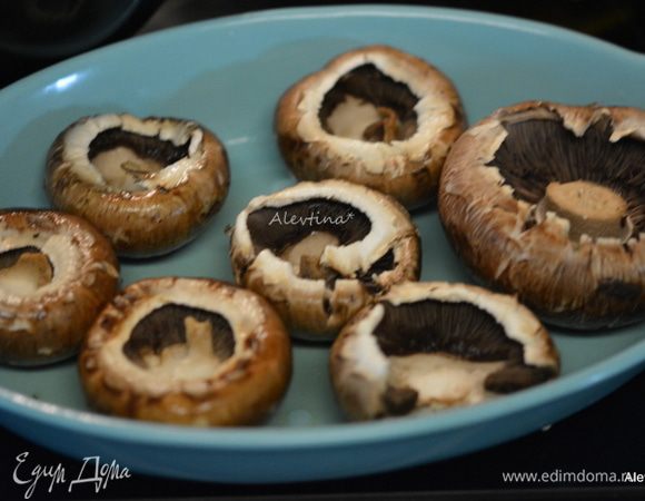 Разогреть духовку до 200°C. Количество шампиньоны примерно на 4 порции, желательно крупные. Помыть, очистить от ножек аккуратно. Смазать блюдо для запекания оливковым маслом 1 ст. л. Выложить грибы на блюдо.