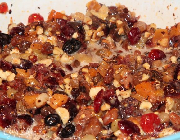 Подготавливаем сухофрукты: чернослив без косточки и курагу нарезаем мелкими кусочками. Изюм, клюкву, вишню моем и просушиваем бумажным полотенцем. С апельсина натираем цедру и выжимаем сок. 120 г очищенного фундука поджариваем на сухой сковороде и крупно рубим ножом. В сотейнике с толстым дном разогреваем масло, добавляем 120 мл рома и сухофрукты, апельсиновый сок, цедру, мед, фундук, ванильный экстракт и сахар. Довести до кипения, уменьшить до минимума нагрев и, осторожно помешивая, дать очень «тихо» покипеть в течение 5-7 минут. Выключить нагрев и отсудить в течение 30 минут (минимум). После того как смесь остынет, добавить взбитые яйца и тщательно вымешать.