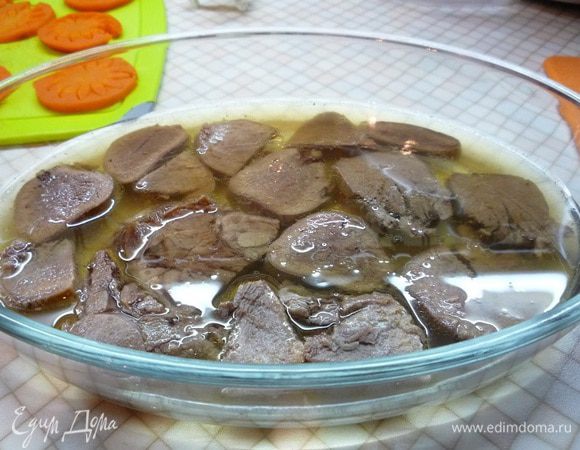 На дно формы выкладываем нарезанные дольками языки, аккуратно заливаем небольшим количеством бульона и убираем в холодильник.