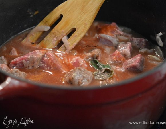 Добавить говядину к луку, налить говяжий бульон, вино. Аккуратно перемешать.