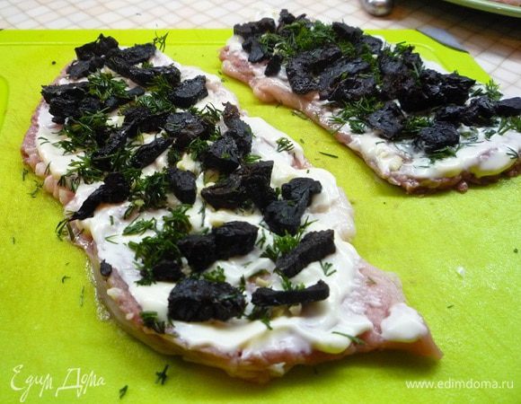 Отбитые кусочки мяса смазываем майонезом и равномерно распределяем начинку: зелень петрушки, рубленный чеснок, чернослив.