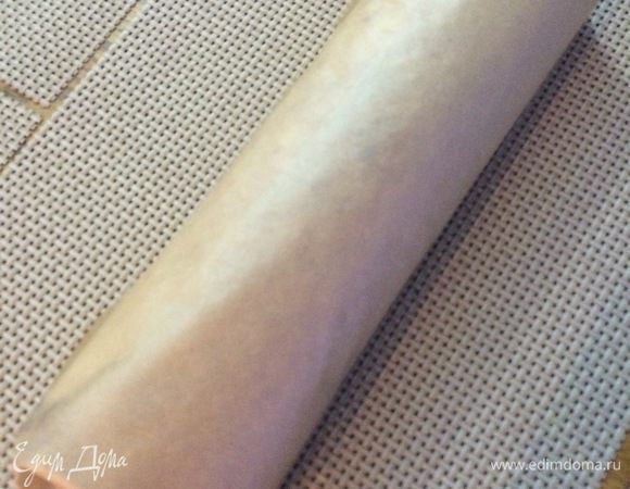 Достаем бисквит из духовки, переворачиваем на полотенце. Снимаем пекарскую бумагу. Закручиваем обратно в рулет и оставляем остывать.