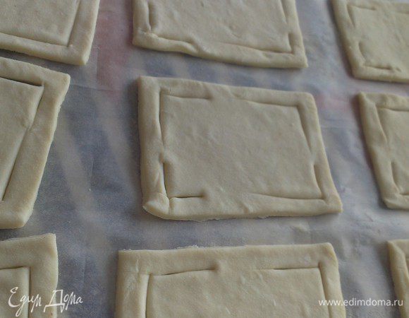 Слегка раскатайте слоеное тесто, разрежьте его на квадраты. По углам каждого квадратика, отступив немного от края, сделайте треугольные разрезы.