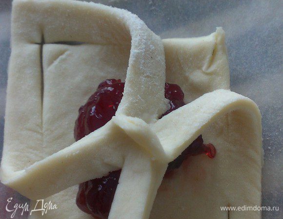 Выложите на противень (у меня он застелен тефлоновой салфеткой). В середину каждого квадрата положите по чайной ложке повидла либо другой нежидкой начинки на ваш вкус. Защипните края: нижний левый с верхним правым. Затем верхний левый и нижний правый.