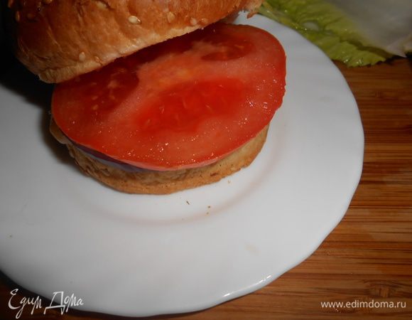 После сразу же пластинку помидора. Помидор я режу перед тем как положить в булку, чтобы сок не стекал на доске. 