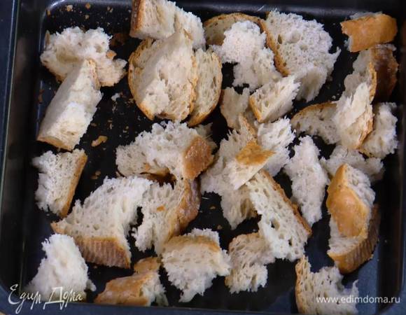 Приготовить крутоны: хлеб поломать руками на неровные кусочки и выложить в небольшой глубокий противень.