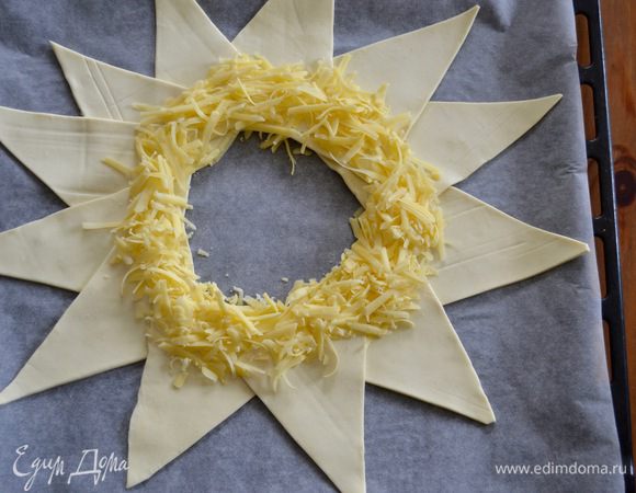 Сыр натереть на терке и выложить слоем по кругу на тесто.