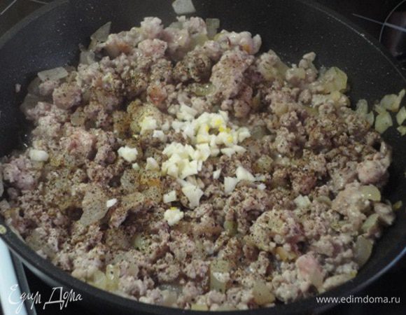 Добавить мясной фарш и помешивать его, чтобы он не взялся комком. Когда фарш побелеет, добавить рубленый чеснок, перец (половину чайной ложки), перемешать, накрыть крышкой и оставить на маленьком огне тушиться.
