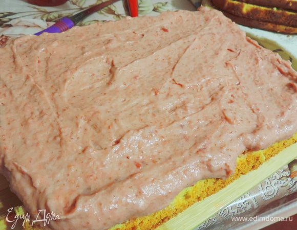 Приступаем к сборке. Выкладываем на блюдо пропитанный бисквитный пласт срезом вверх. Смазываем половиной клубничного крема.