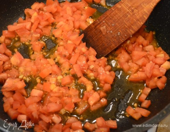 Затем его выложить из сковородки и на ней же обжарить сперва мелко порубленный чеснок, добавить порезанные кубиком помидоры. Тушить около 5 минут. Добавить томатную пасту. Этот момент можно и пропустить, если у вас сезонные сочные и ароматные помидоры. У меня же зимние покупные, которые лишь издалека напоминают помидор.