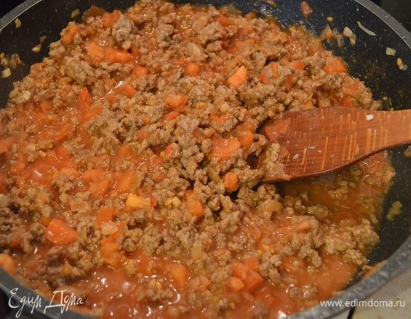 К томатам в сковородку выкладываем половину поджаренного ранее лука и фарш. Томим на медленном огне около 5 минут.