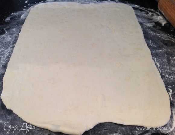 Присыпьте стол мукой и раскатайте половину теста. Выложите на противень. 