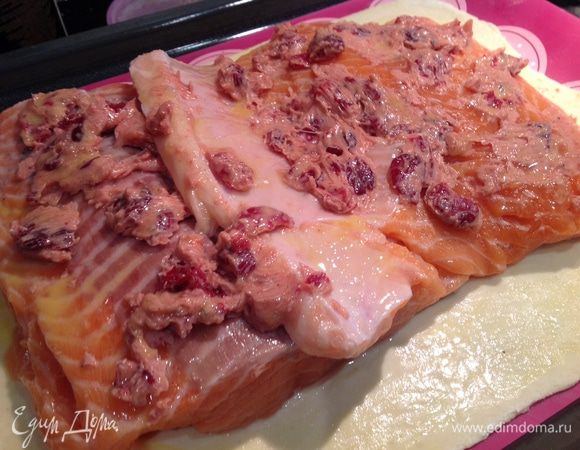 Филе лосося смажьте со всех сторон ароматным маслом с клюквой и выложите на тесто. Смажьте филе и кромку теста взбитым яйцом.