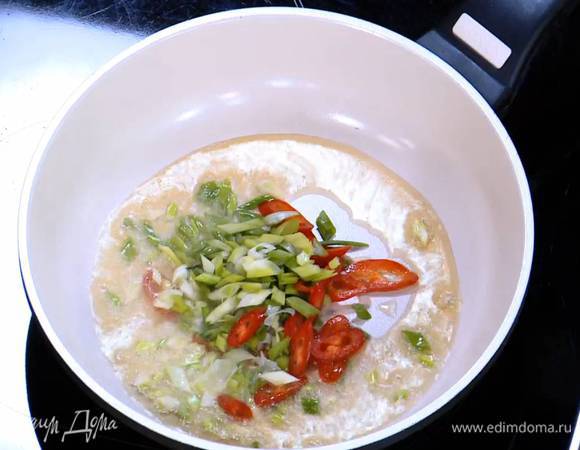 Разогреть в сковороде кунжутное и оливковое масло и обжарить зеленый лук и чили.