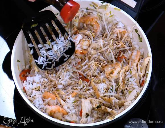 Добавить готовый рис, перемешать и немного обжарить, затем влить соевый соус, еще раз все перемешать.