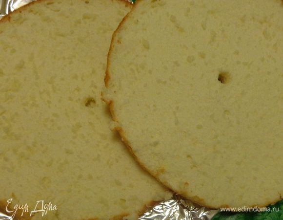 Разрезать бисквит на пласты, пропитать их сиропом с коньяком (опционно), промазать кремом.