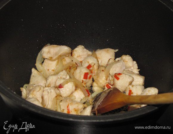 Разогреем в воке или сотейнике, растительное масло, обжарим в нем острый перец и чеснок в течении 30 секунд, добавим кусочки курицы и репчатый лук. Жарим 5 минут, постоянно помешивая.