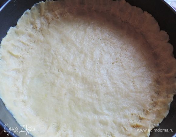 Берем разъемную форму диаметром 26 см. Дно выстилаем бумагой для выпечки. Тесто равномерно распределяем по дну и бокам, формируя бортики высотой примерно 2,5 см.  Слой теста получается тоненьким. 
Убираем форму в холодильник на время приготовления начинки.
