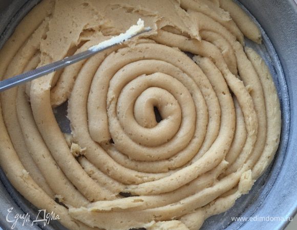 "Выжимаем" тесто (половину) по спирали в форму. Оно достаточно густое, надо поднапрячься. Смоченным водой ножичком, выравниваем наше тесто.
