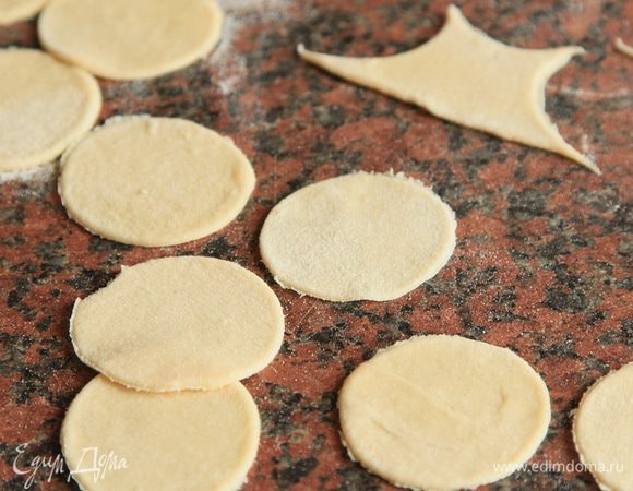 Теперь отрезаем от теста небольшими порциями, раскатываем очень тонко — яйцо нам позволяет это делать. Я раскатываю тесто очень тонко, оно у меня получается толщиной меньше 1 мм. И рюмочка у меня есть специальная, диаметр по внутреннему ободку 4,5 см, ею я и вырезаю кружочки под пельменьки. 