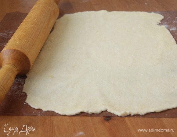 Через указанное время достать один кусок теста, раскатать в прямоугольник, примерно 20х30 см. Раскатывать сразу на пекарской бумаге или антипригарном коврике.