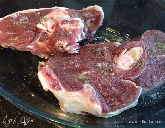 Духовку разогрейте до 180°C. Баранину промойте, обсушите бумажным полотенцем, натрите перцем и солью, и выложите на дно огнеупорной формы. 