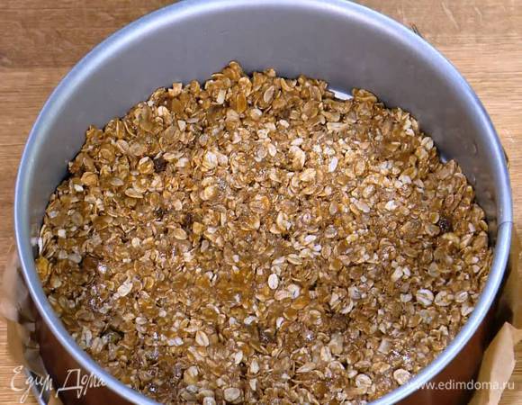 Разъемную форму для выпечки выстелить пищевой бумагой, смазанной растительным маслом, выложить тесто и утрамбовать его.