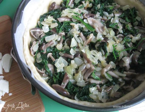 Вынуть форму из холодильника, на тесто положить нижний слой из опят с луком и шпинатом. Сверху — кусочки моцареллы.


