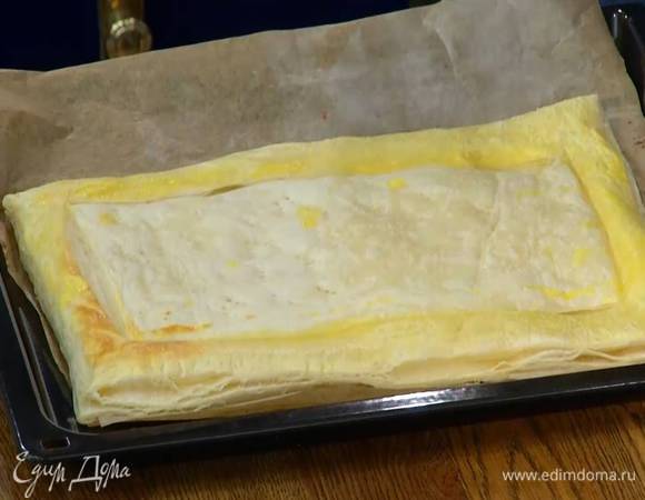 Все тесто, кроме бортиков, часто наколоть вилкой, поместить на противень, выстеленный бумагой для выпечки и отправить в разогретую духовку на 5 минут.