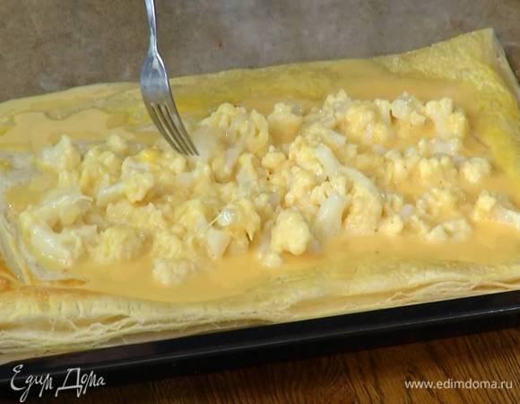 Подпеченный корж вынуть из духовки и равномерно выложить на него капустную начинку, оставив бортики свободными.