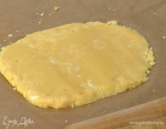 Поместить тесто на бумагу для выпечки, руками сформировать пласт, накрыть вторым листом бумаги и слегка раскатать скалкой, так чтобы получился пласт толщиной в 1 см.